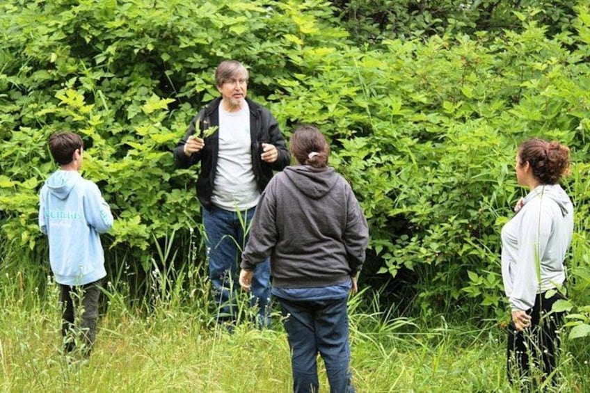 Un groupe de personnes se tient dans une zone herbeuse, avec un feuillage vert et dense en arrière-plan. 4
