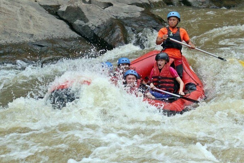 A group of people in a red raft navigating through a river with rapids. 4