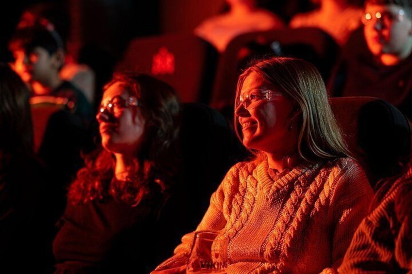 Mensen zitten in een zwak verlicht theater. 3