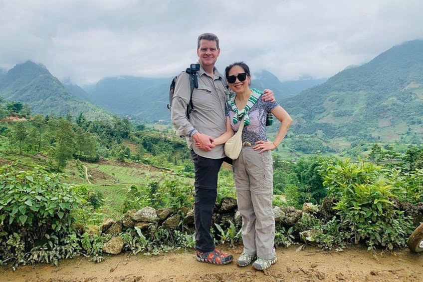 Two people standing on a dirt path with a mountainous landscape in the background. 5