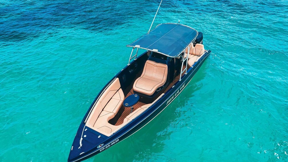 Un bateau à moteur rapide doté d’un toit, de sièges beiges et d’une coque bleue, naviguant sur une eau turquoise. 3