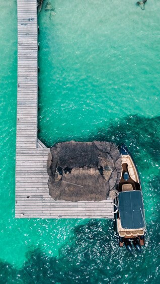 Une vue aérienne d’une jetée en bois s’étendant dans une eau turquoise, avec un bateau amarré à son extrémité. 5