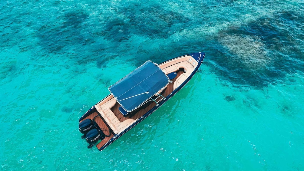 Vue aérienne d’un bateau dot é d’un auvent bleu et d’un pont en bois, flottant sur une eau turquoise. 4