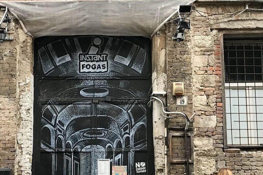 A black door with graffiti, a number '49' sign, and a 'NO DRINKING' sign. 3