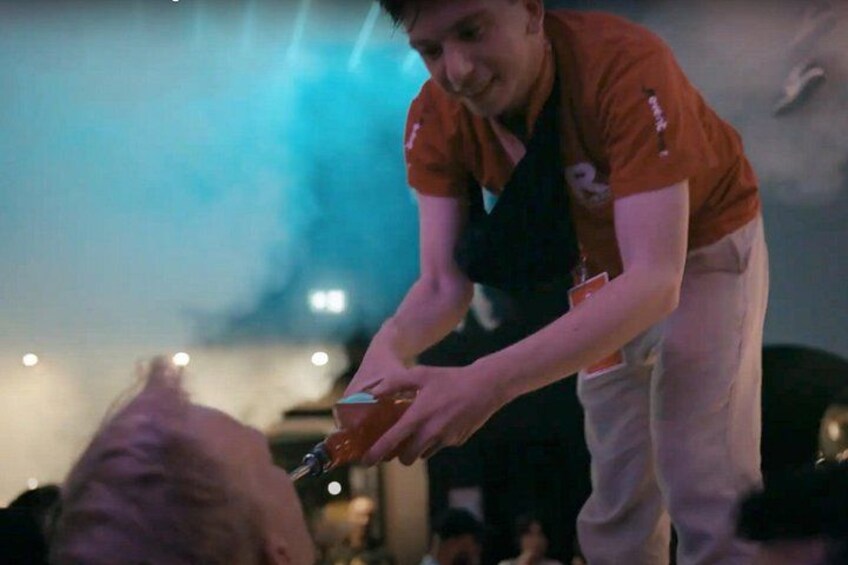 A person in an orange shirt pouring a drink. 2