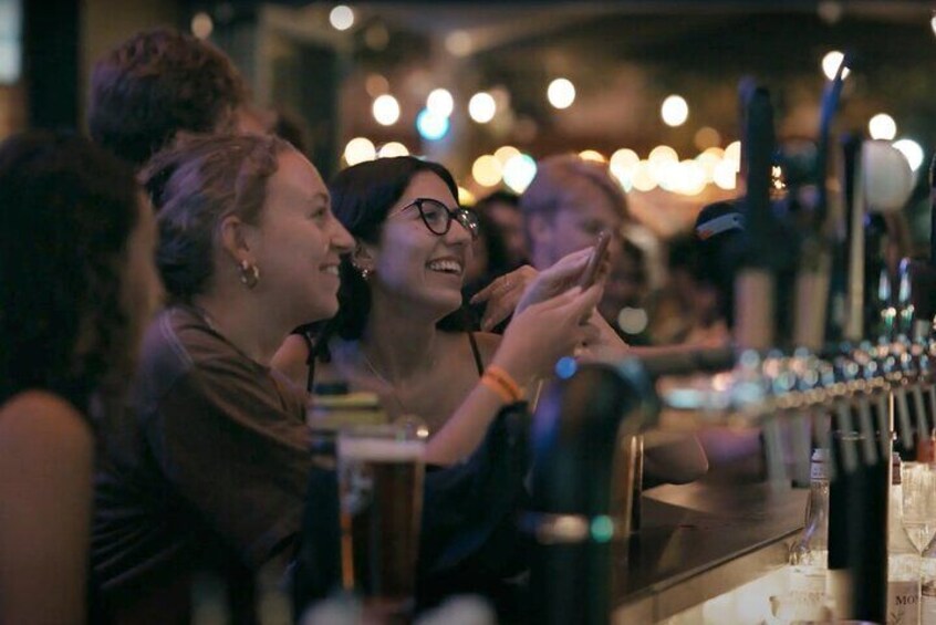 Un groupe de personnes est assis au bar, devant des boissons et des verres. 5