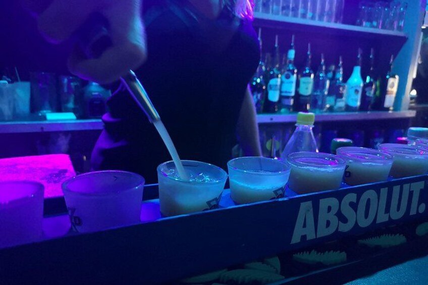 A bar setting with various drinks and bottles, including a prominent Absolut sign. 4