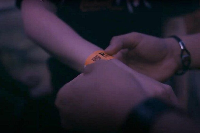 A person placing a wristband on another person's wrist. 3