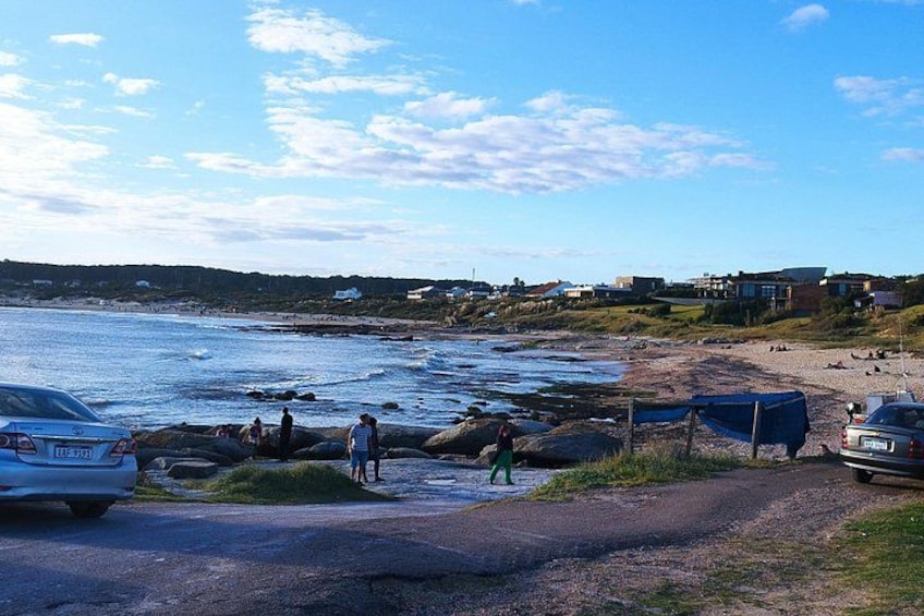 Una carretera costera con coches aparcados, una playa y gente cerca del agua. 5