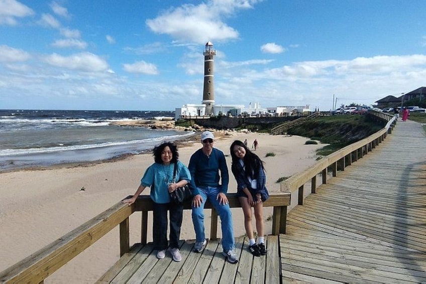 Una pasarela de madera, una playa y un faro al fondo. 3