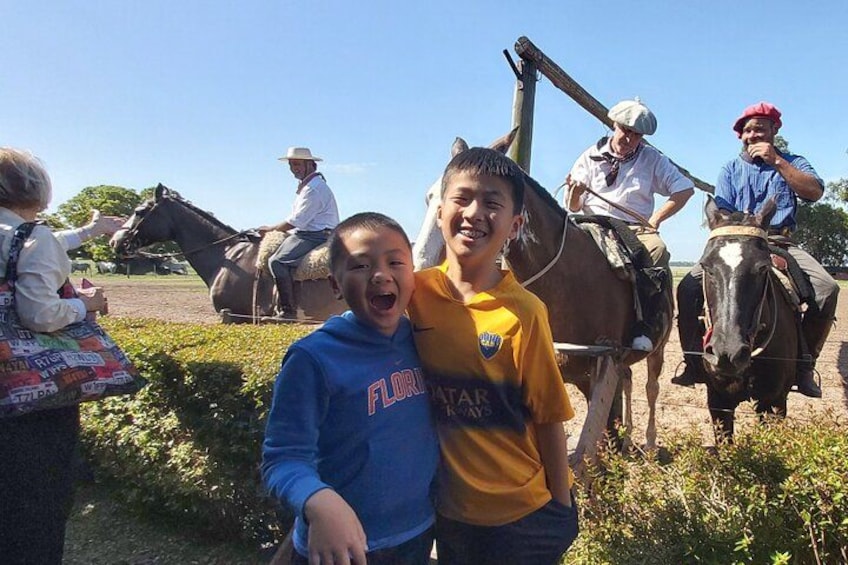 Due bambini in un campo con cavalli e persone a cavallo. 3