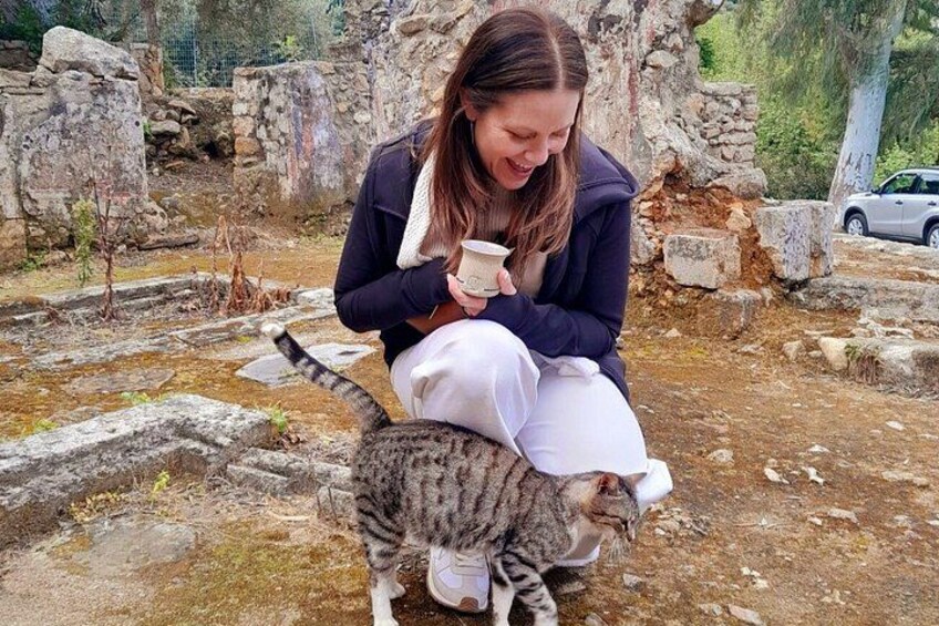 Iemand zit op een stenen constructie met een kat, omringd door ruïnes. 3