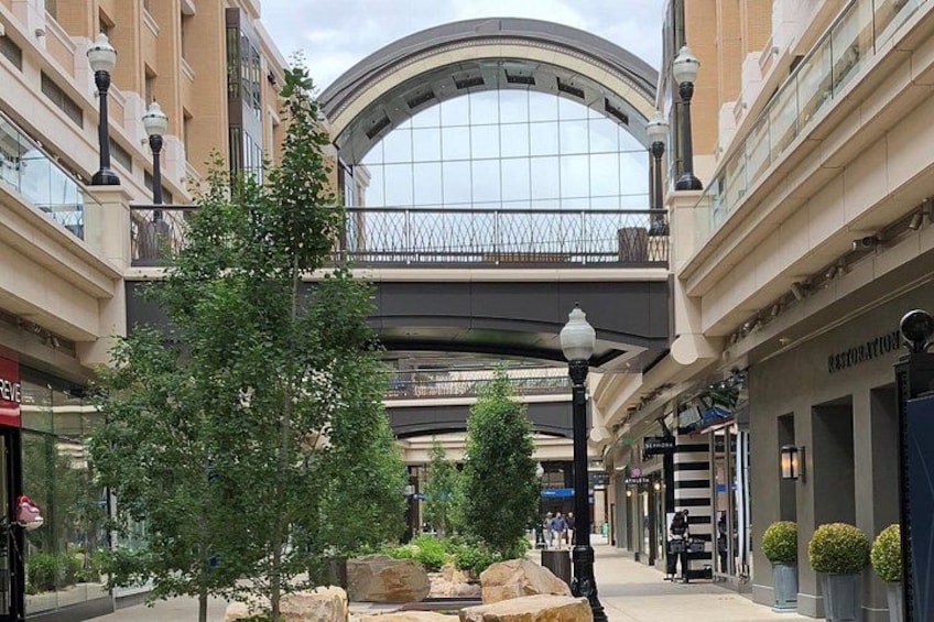 Un centre commercial doté d’un toit en verre, d’arbres et d’une fontaine en pierre. 4
