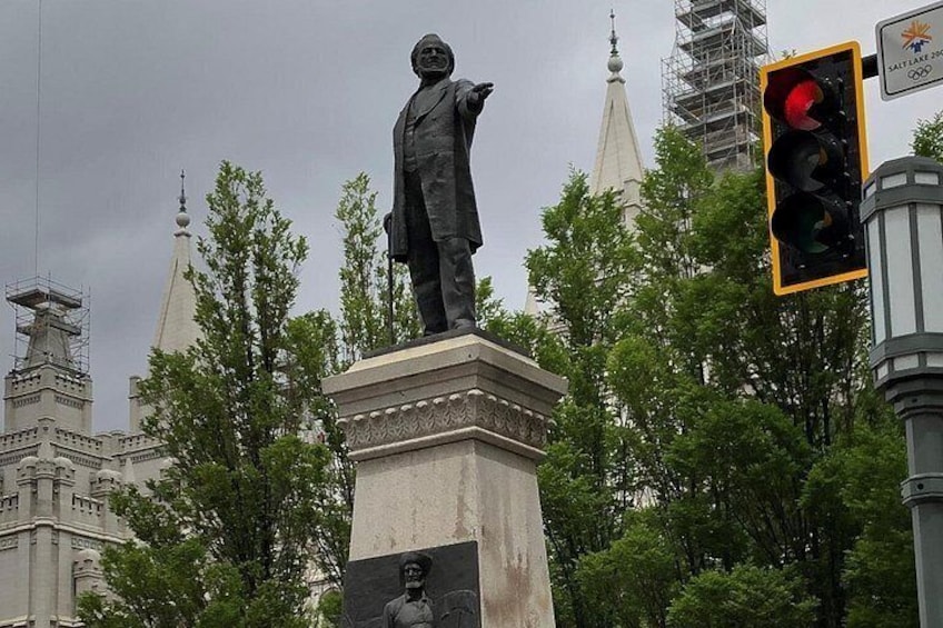 Una estatua de un hombre sobre un pedestal, rodeada de árboles y edificios. 3