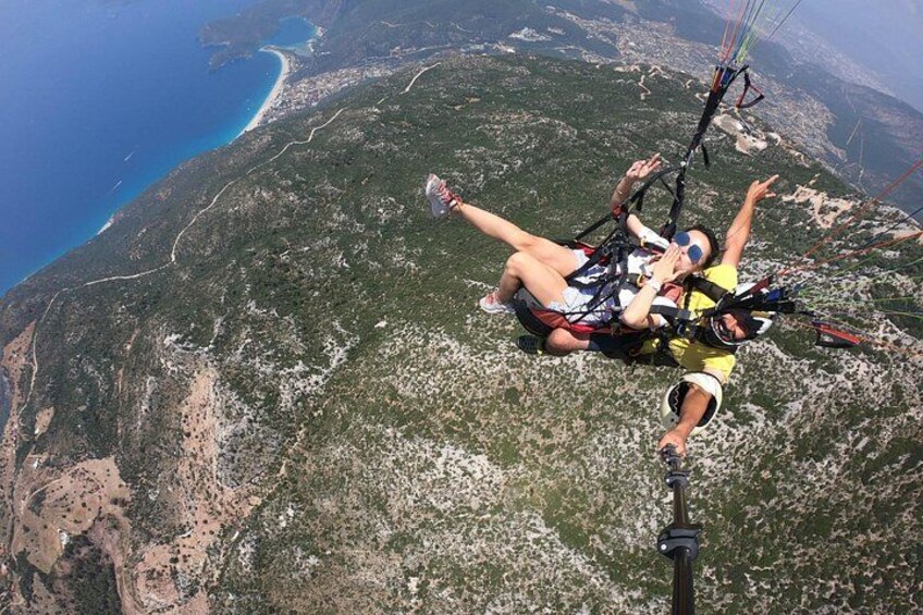Dos personas practicando parapente sobre un paisaje montañoso con una costa al fondo. 5