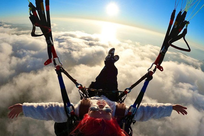 Una persona vola in parapendio sopra le nuvole, con paracadute e imbracatura. 2
