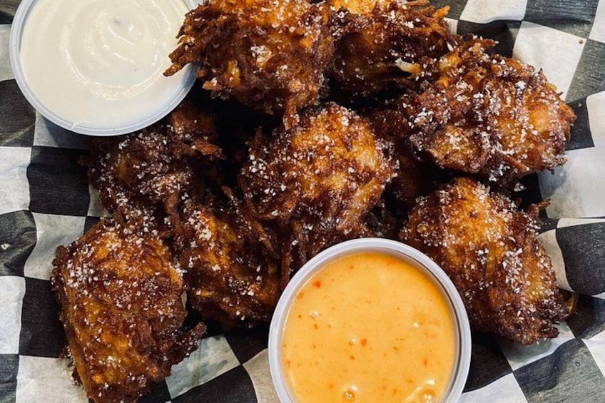 A plate of fried chicken wings with a side of dipping sauces. 5