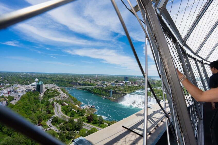 Eine Person auf einer Brücke mit Blick auf eine Stadt, einen Fluss und einen Wasserfall. 3