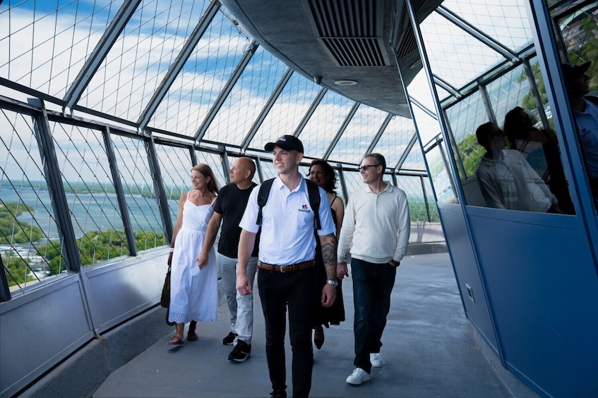 Eine Gruppe von Menschen geht über eine Glasbrücke mit Blick auf die Landschaft darunter. 2