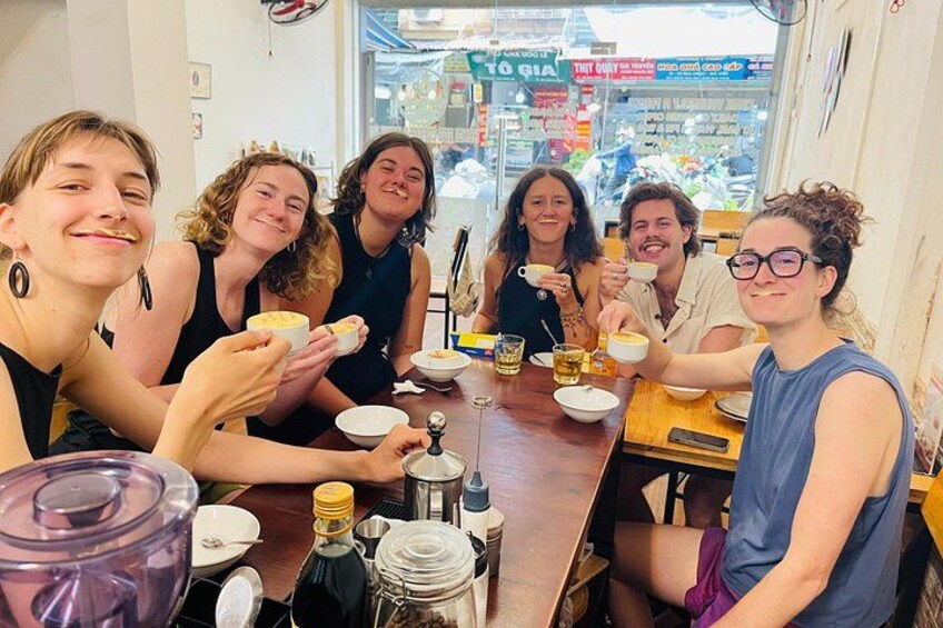Un grupo de personas sentadas en una mesa de madera, comiendo y bebiendo. 1
