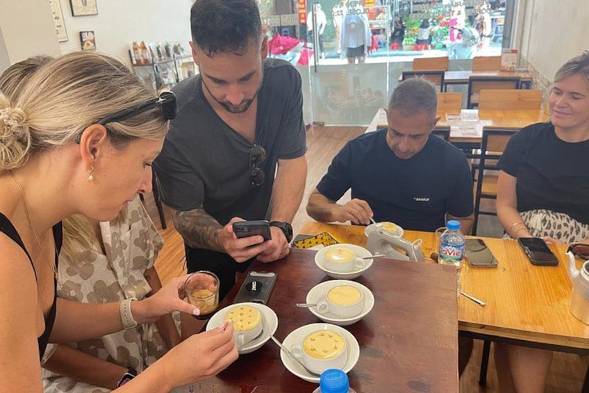 Un grupo de personas sentadas en una mesa de madera en un café, con tazas de café y un teléfono inteligente sobre la mesa. 2