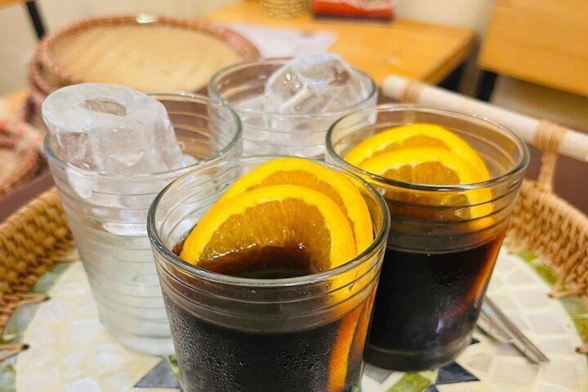 Drie glazen ijsthee met oranjeslices, een glas water en een glas ijsthee met rietje. 3