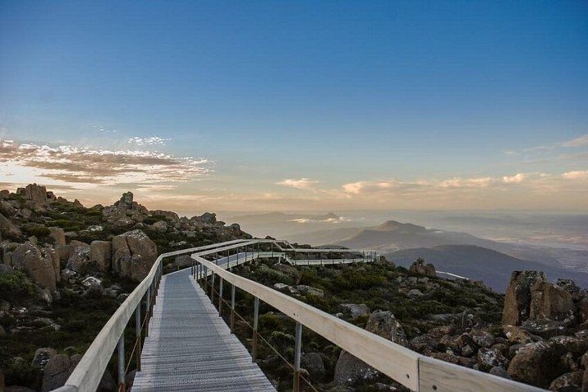 A wooden boardwalk leading to a viewpoint overlooking a mountainous landscape. 4