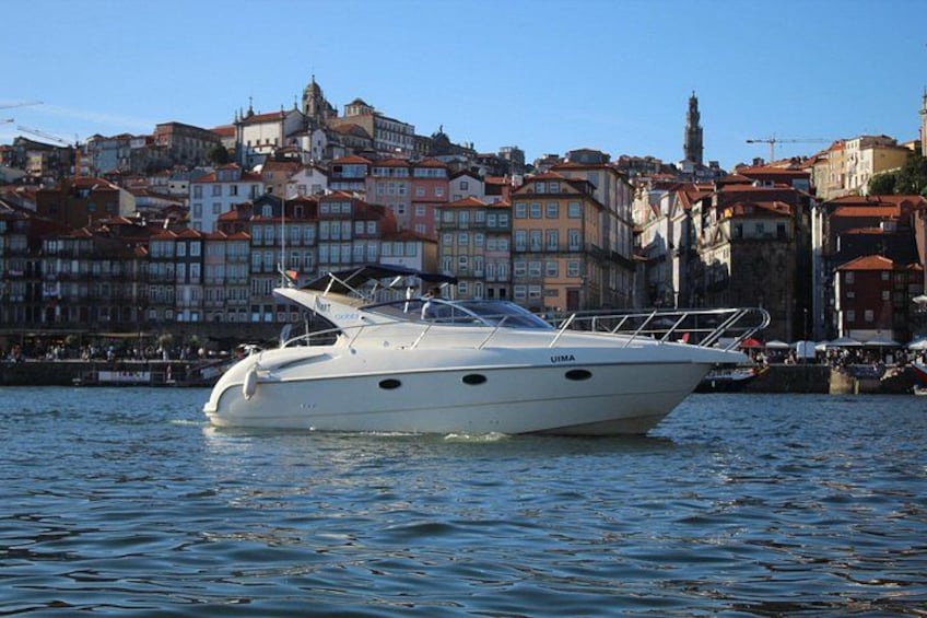 A white yacht named UMA on calm water, with a cityscape in the background. 1