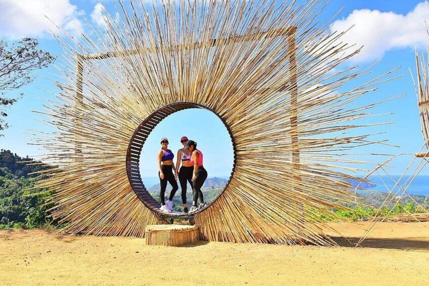 Two people standing in a circular frame made of sticks, with a mountainous landscape in the background. 3