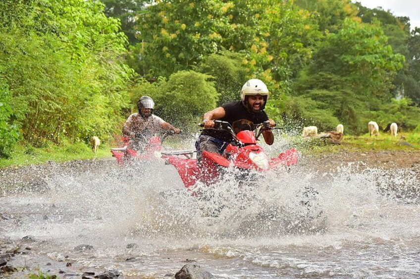 Two people on red motorcycles splashing through water. 4