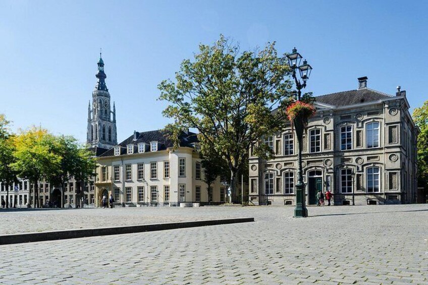 Ein Kopfsteinpflasterplatz mit historischen Gebäuden, einem Kirchturm und einer Straßenlaterne. 3