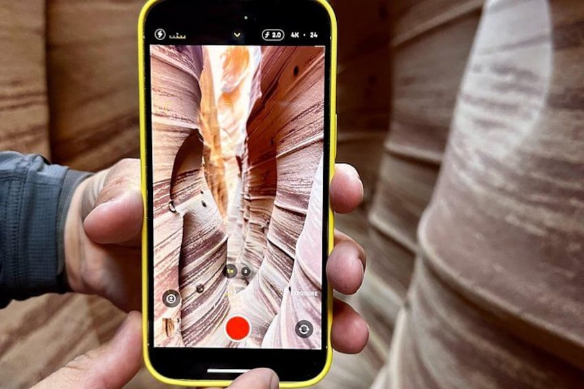 A person holding a smartphone displaying a canyon with a red circle at the bottom. 3