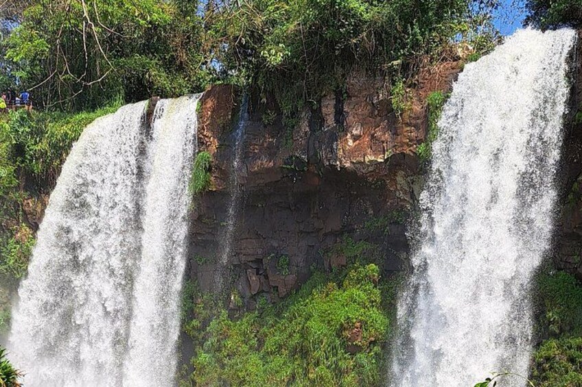A waterfall with multiple streams cascading down a rocky cliff, surrounded by lush greenery. 4