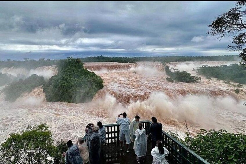 A group of people observing a large waterfall. 5