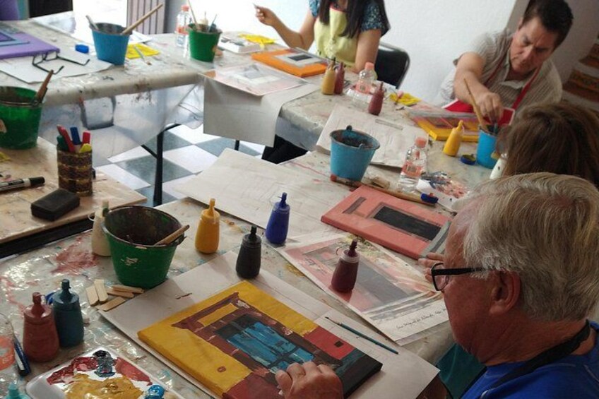 A group of people engaged in a painting activity at a table with art supplies. 4