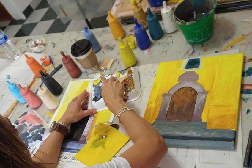 A person painting a picture with various art supplies on a table. 2
