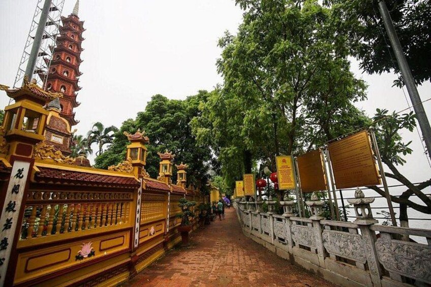 A temple with a red pagoda, a stone bridge, and a pathway lined with trees. 3