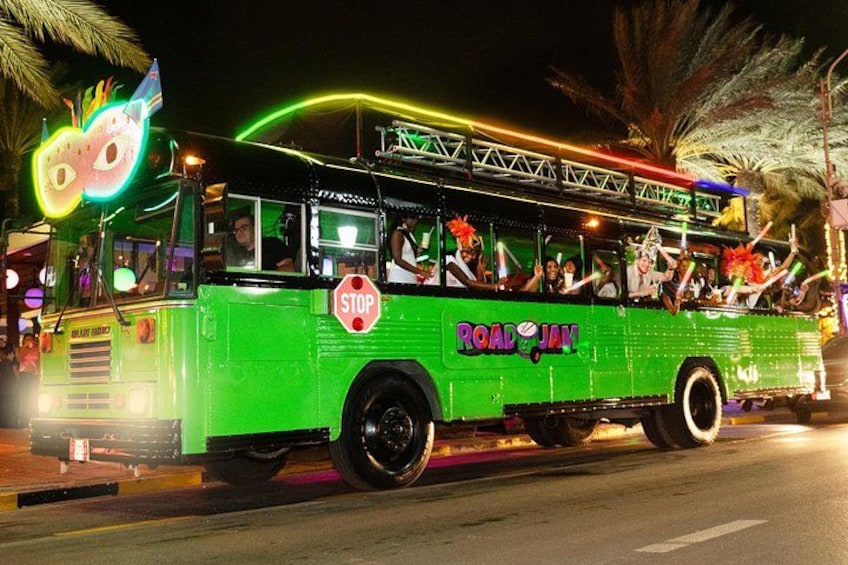 Un autobus dai colori vivaci con la scritta 'ROAD JAM', che percorre una strada di notte. 4