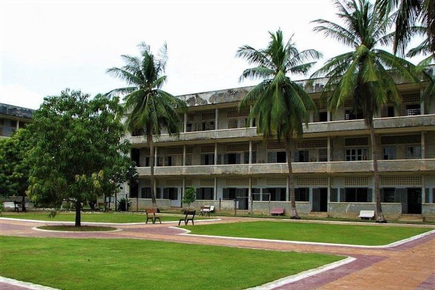 A multi-story building with palm trees and a grassy courtyard. 4