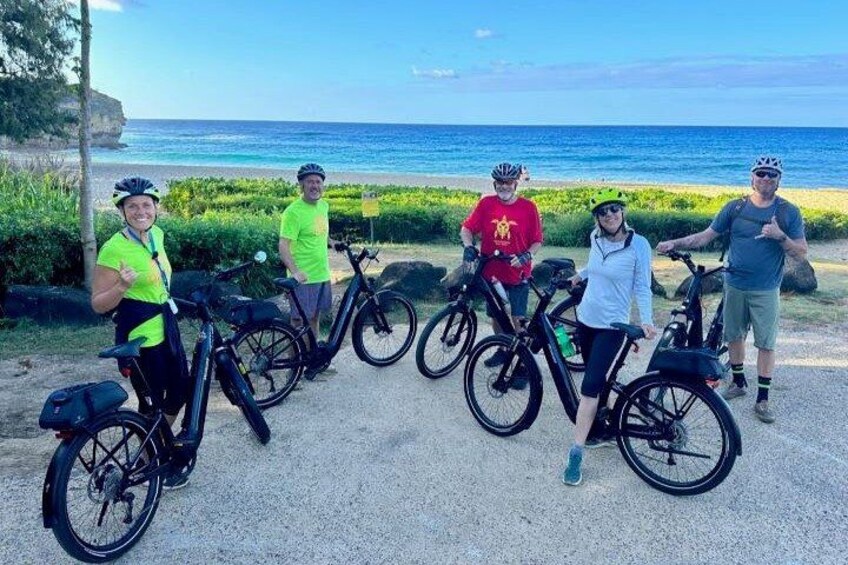 A group of people with bicycles by a coastal road. 1