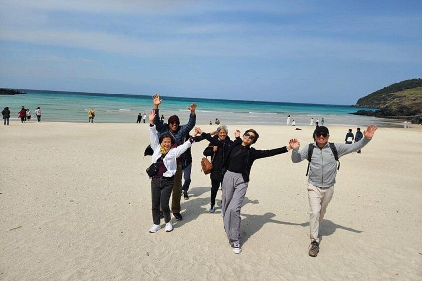 Een groep mensen op een zandstrand, met de oceaan op de achtergrond. 4