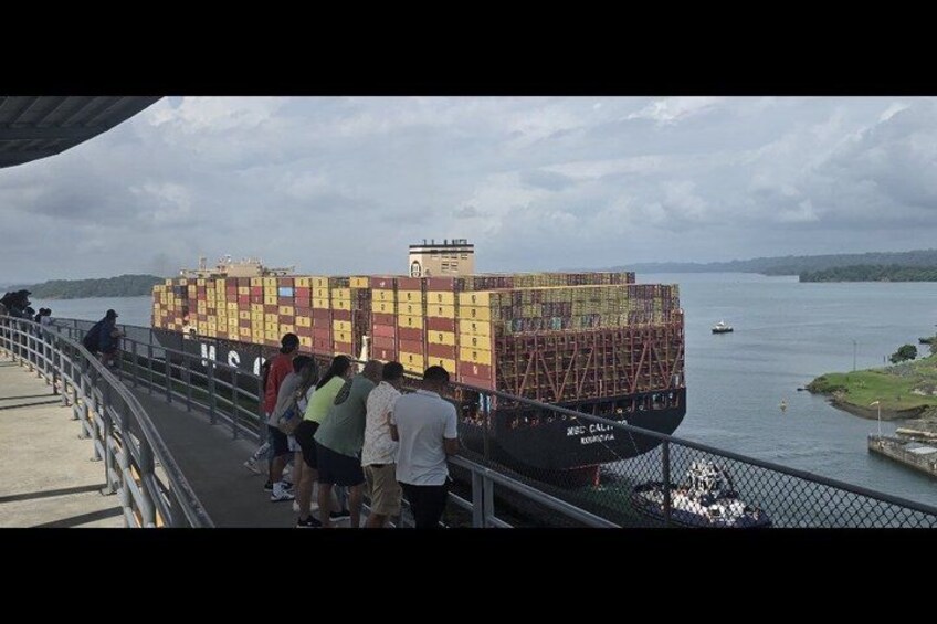 Et fragtskib lastet med farverige containere ligger ved kaj i en havn. 4