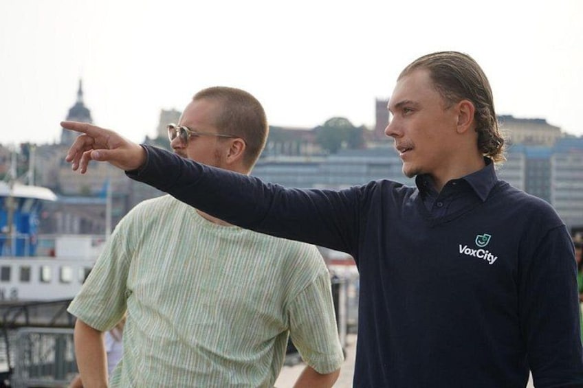 Two individuals in a city setting, one pointing towards the horizon. 2