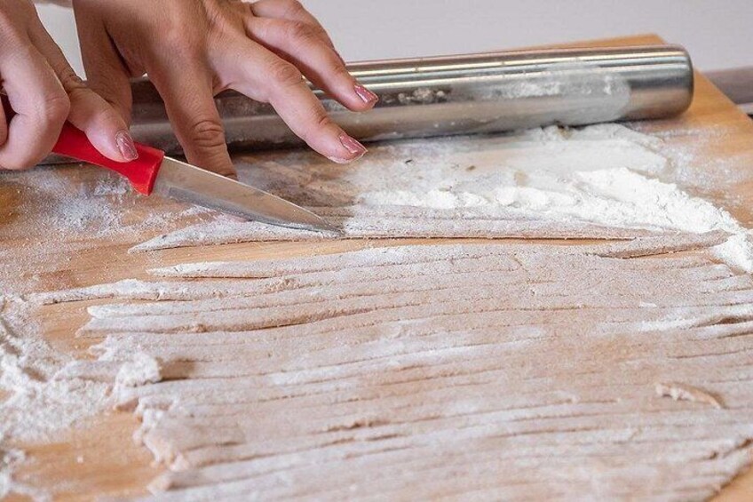 Hands using a rolling pin on flour on a wooden surface. 2