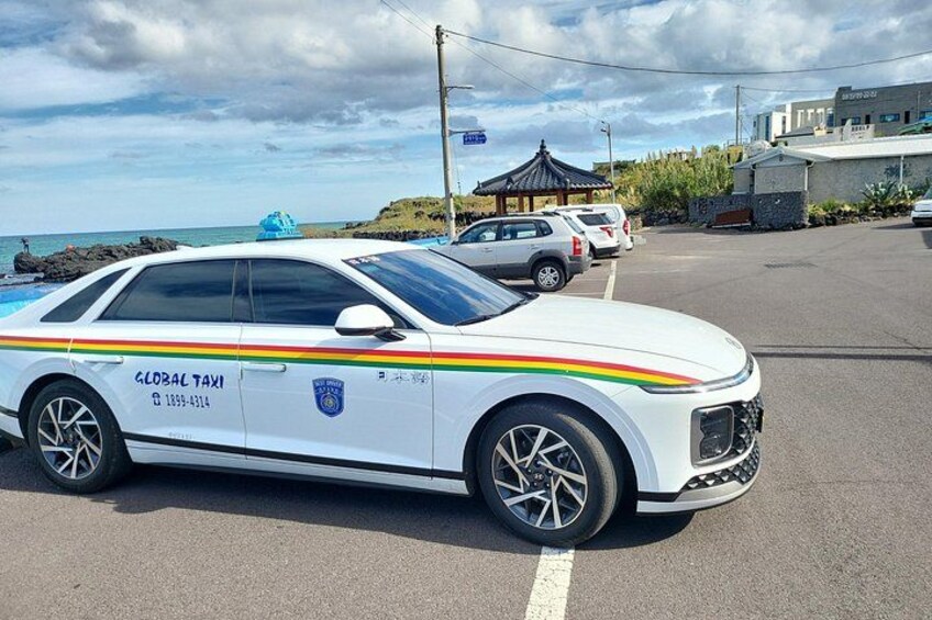 A white Global Taxi car with a blue roof parked in a lot. 2
