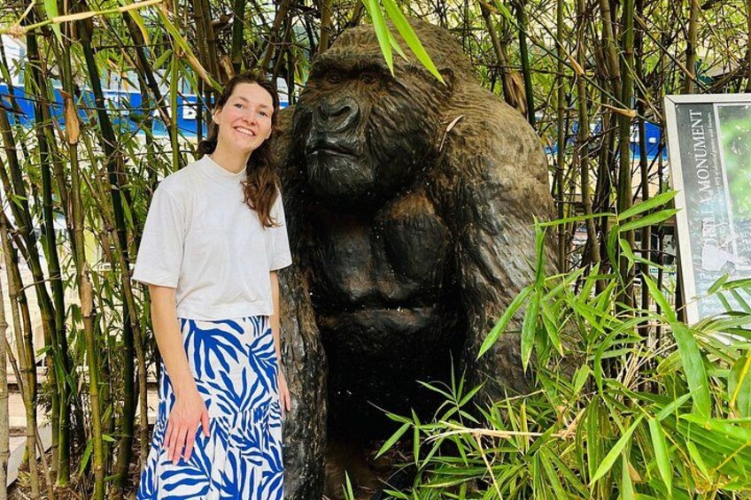 A person standing next to a gorilla statue in a bamboo forest. 5