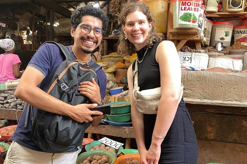 Two people at a market stall with various food items and containers. 4