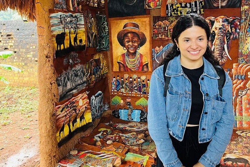 A person standing in front of a wall with various artworks and a mural. 2