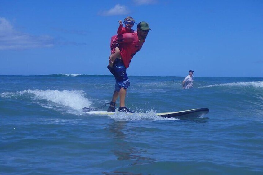 Una persona surfeando mientras otra persona está de pie sobre sus hombros en el océano. 1