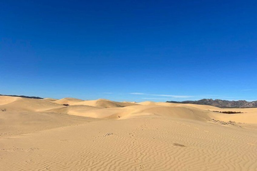 A desert landscape with sand dunes and a clear blue sky. 2